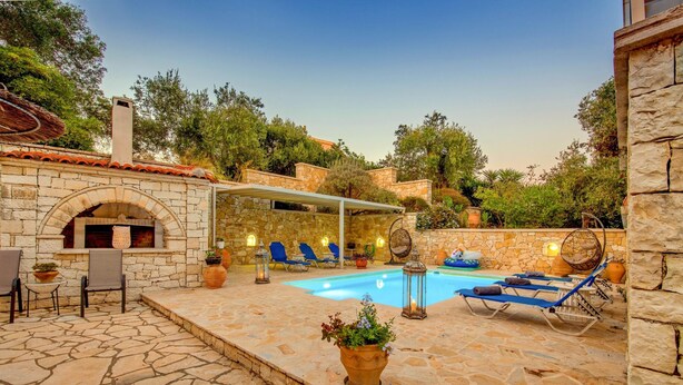 A stone patio with a pool, lounge chairs, and a stone fireplace. - Villa Divista in Paxi (Paxos)