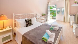 A modern hotel room with a bed, bedside table, lamp, and a view of the garden. - Villa Divista in Paxi (Paxos)