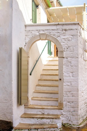 A narrow staircase leading up to a door with a metal handrail.
