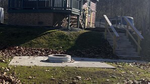 A two-story cabin with a balcony, a stone foundation, and a wooden staircase leading to the upper level.