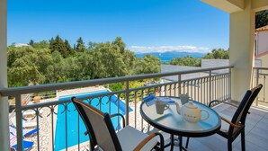 Un balcon avec une table et des chaises, donnant sur une piscine et offrant une vue panoramique sur les arbres et les montagnes.