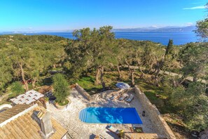 A pool area with a view of the sea, surrounded by trees and stone architecture. - Villa Lenio Paxos in Anemogiannatika (Paxos)