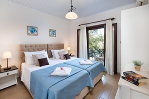 Une chambre avec deux lits, une table de chevet, une table avec une plante et un balcon avec vue.