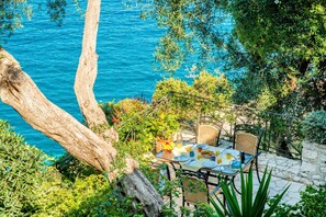 A dining table set outdoors with chairs, overlooking a body of water.