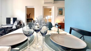 A dining table set with multiple wine glasses, plates, and cutlery, with a television and decorative items in the background. - Casa Lumi a in Syracuse (Syracuse)