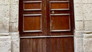 A large, ornate wooden door with a metal grille above it, set within a stone building with intricate carvings. - Casa Lumi a in Syracuse (Syracuse)