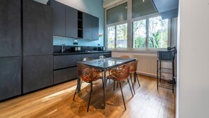 A modern kitchen with dark cabinets, a glass-top table, and copper chairs. - Loft Porta Maggiore in Rome (Rome)