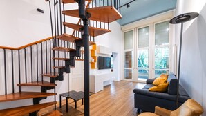 A modern living space with a wooden staircase, a black floor lamp, and a sofa with yellow cushions. - Loft Porta Maggiore in Rome (Rome)