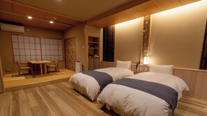 A hotel room with two beds, a sitting area with a table and chairs, and a wardrobe. - Kyou Gohan to Rotenburo no Yado Yunohanatsukiya (Kameoka)