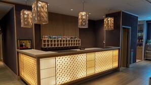 A reception area with a wooden reception desk, pendant lighting, and a wall-mounted shelf with framed pictures. - Kyou Gohan to Rotenburo no Yado Yunohanatsukiya (Kameoka)