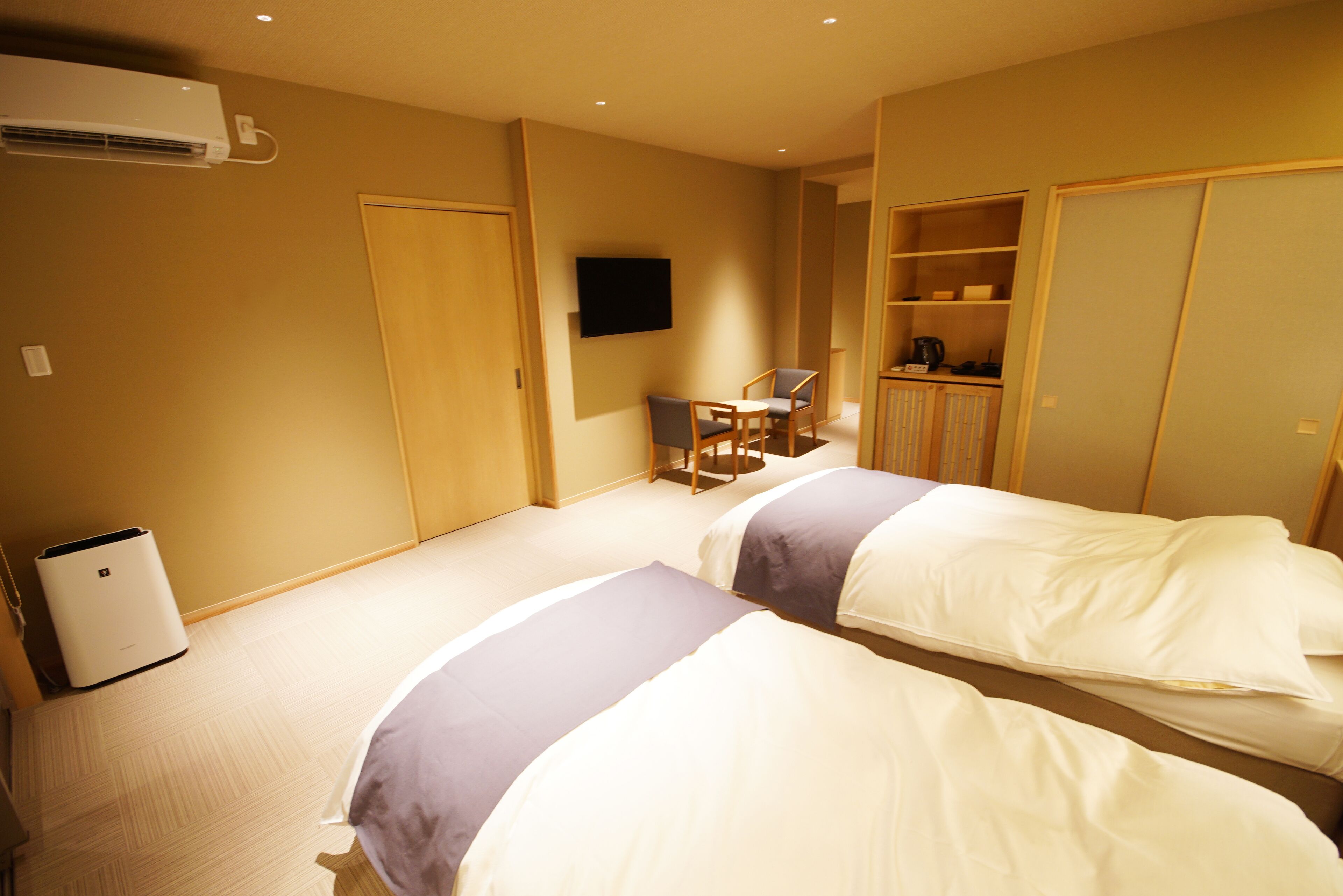 A hotel room with two beds, a TV, a desk, and a wardrobe.