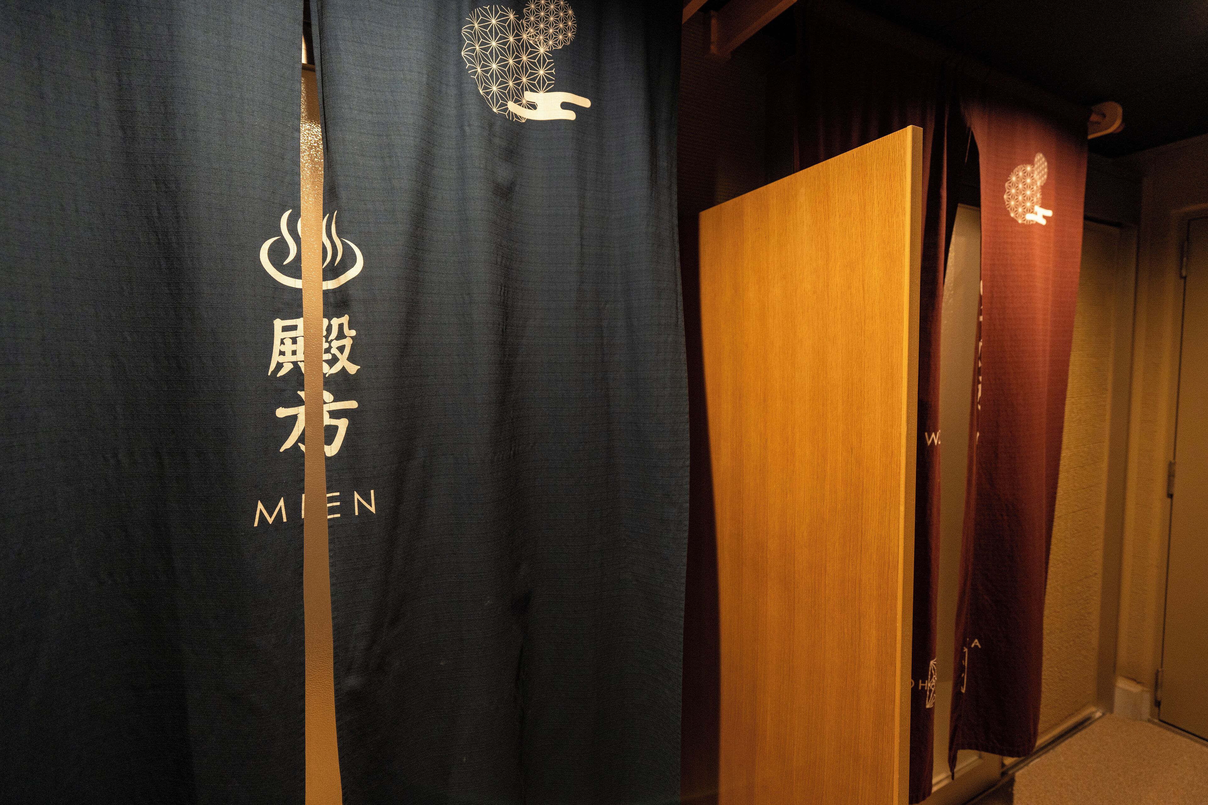A room with a dark curtain featuring gold text and a wooden door.