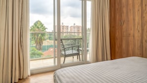 A bedroom with a large window, a wooden wardrobe, and a bed. - Kikambala Modern Apartment with Balcony (Nairobi)