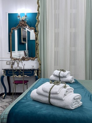 A hotel room with a bed, a vanity with a mirror, a desk, and a chair. There are towels on the bed. - Property Palazzo Caldarulo (Polignano a Mare)