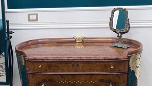 A vintage wooden dresser with a mirror and a gold-framed mirror above it, set against a teal wall. - Property Palazzo Caldarulo (Polignano a Mare)