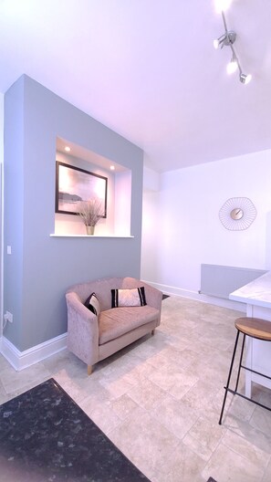 A modern living room with a light blue wall, a beige sofa, a small table, and a decorative wall clock.