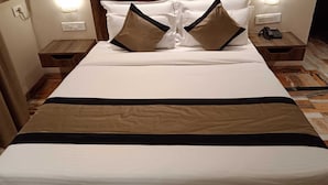 A hotel room with a large bed, two bedside tables, a telephone on one table, and a wall socket. - I Towne (Deoghar)