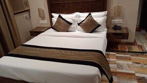 A neatly made bed with a white and brown bedspread, two bedside tables with lamps, and a patterned floor. - I Towne (Deoghar)