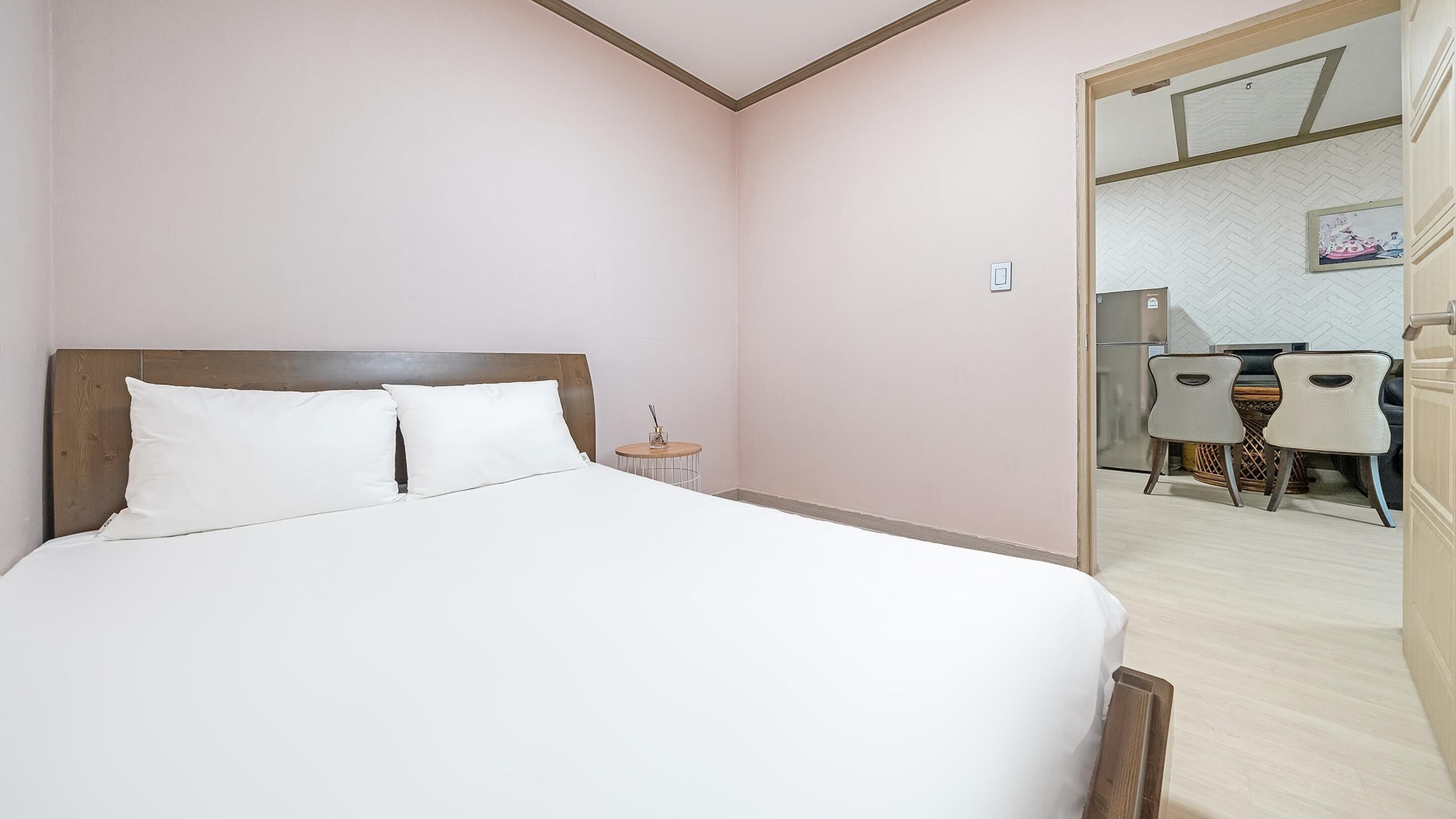 A bedroom with a bed, a bedside table, and a small round table with a lamp.