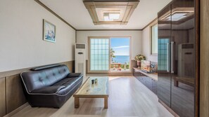 Una sala de estar moderna con un sofá de cuero, una mesa de centro de madera y vista al mar a través de amplios ventanales.