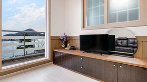 Una sala de estar moderna con un ventanal grande, un televisor de pantalla plana, un sofá de cuero y un mueble de madera.