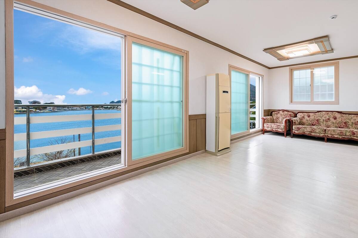 A spacious room with large windows, a sofa, and a ceiling light fixture.