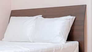 Un lit avec une literie blanche et une tête de lit en bois.