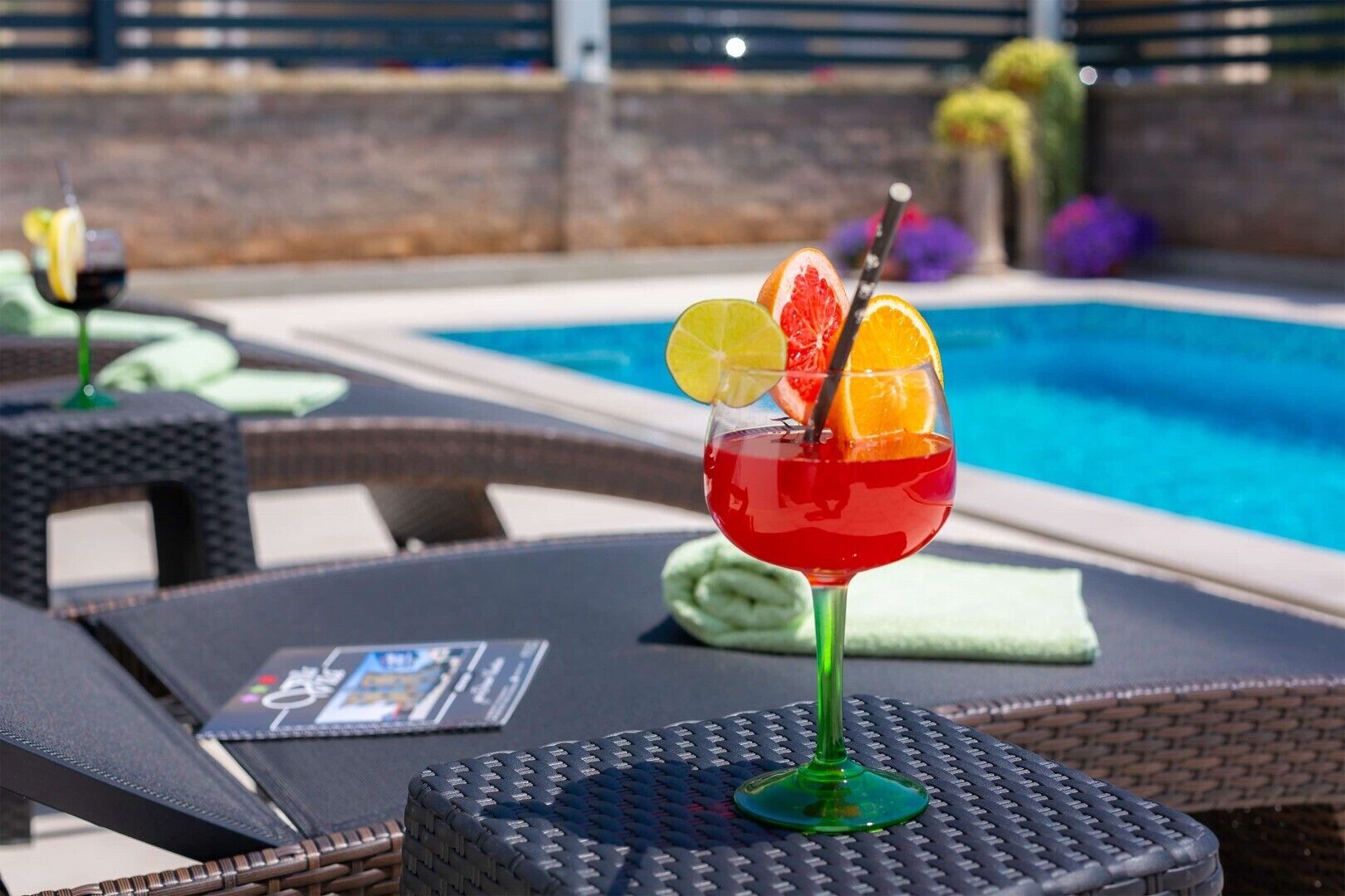 A poolside setting with lounge chairs and a cocktail glass with fruit garnish.