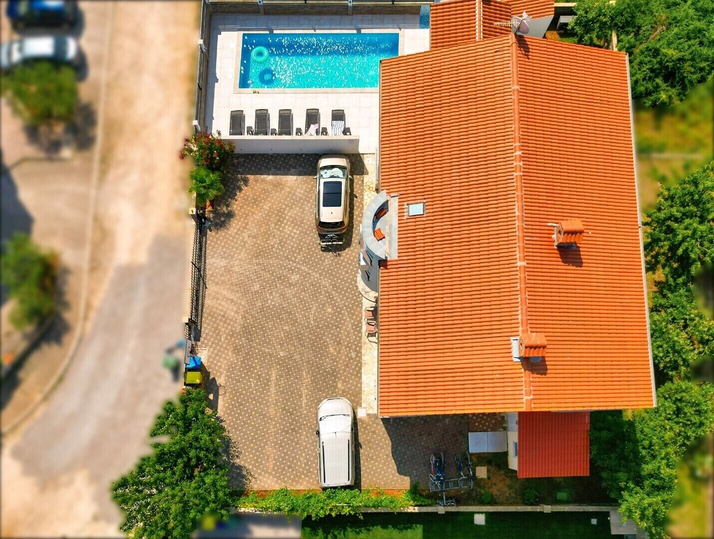 Vista aérea de una propiedad con piscina, un porche cubierto y un edificio de techo rojo.