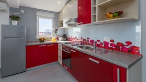A modern kitchen with red and white cabinetry, a stainless steel refrigerator, and a window with a view.