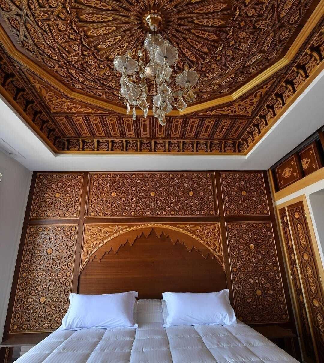 Una habitación con una cama grande, techo decorado y una araña.