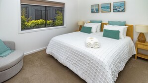 Un dormitorio con una cama grande, una ventana con vistas a zonas verdes y dos cuadros en la pared.