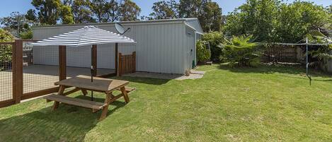 A backyard with a picnic table, a covered area, and a shed.