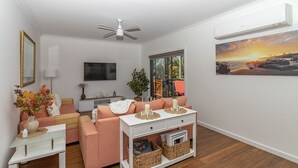Una sala de estar moderna con un juego de sofá, una mesa de centro, un televisor y un cuadro en la pared.