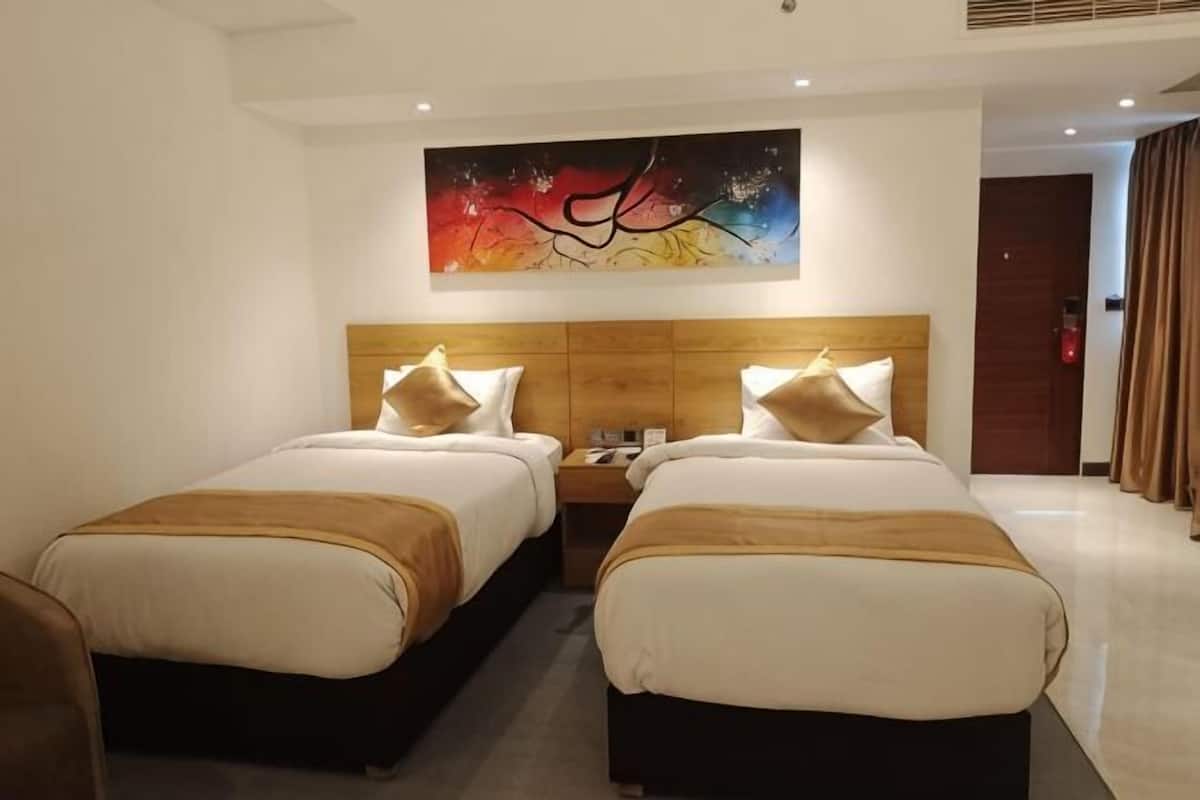 A hotel room with two beds, a wooden headboard, a nightstand, and a wall painting.