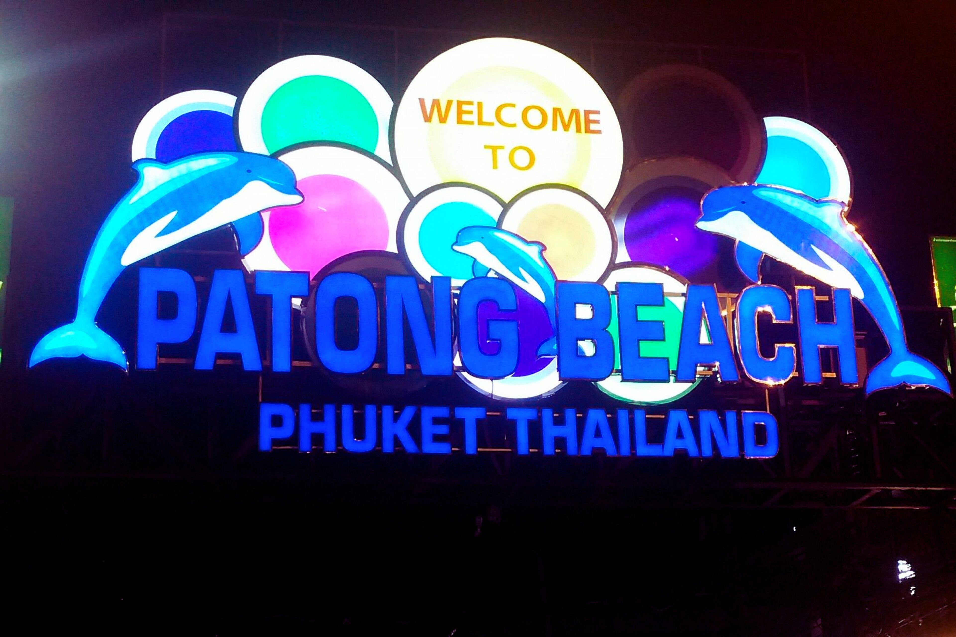 A neon sign with the text "Welcome to Patong Beach Phuket Thailand" and dolphin graphics.