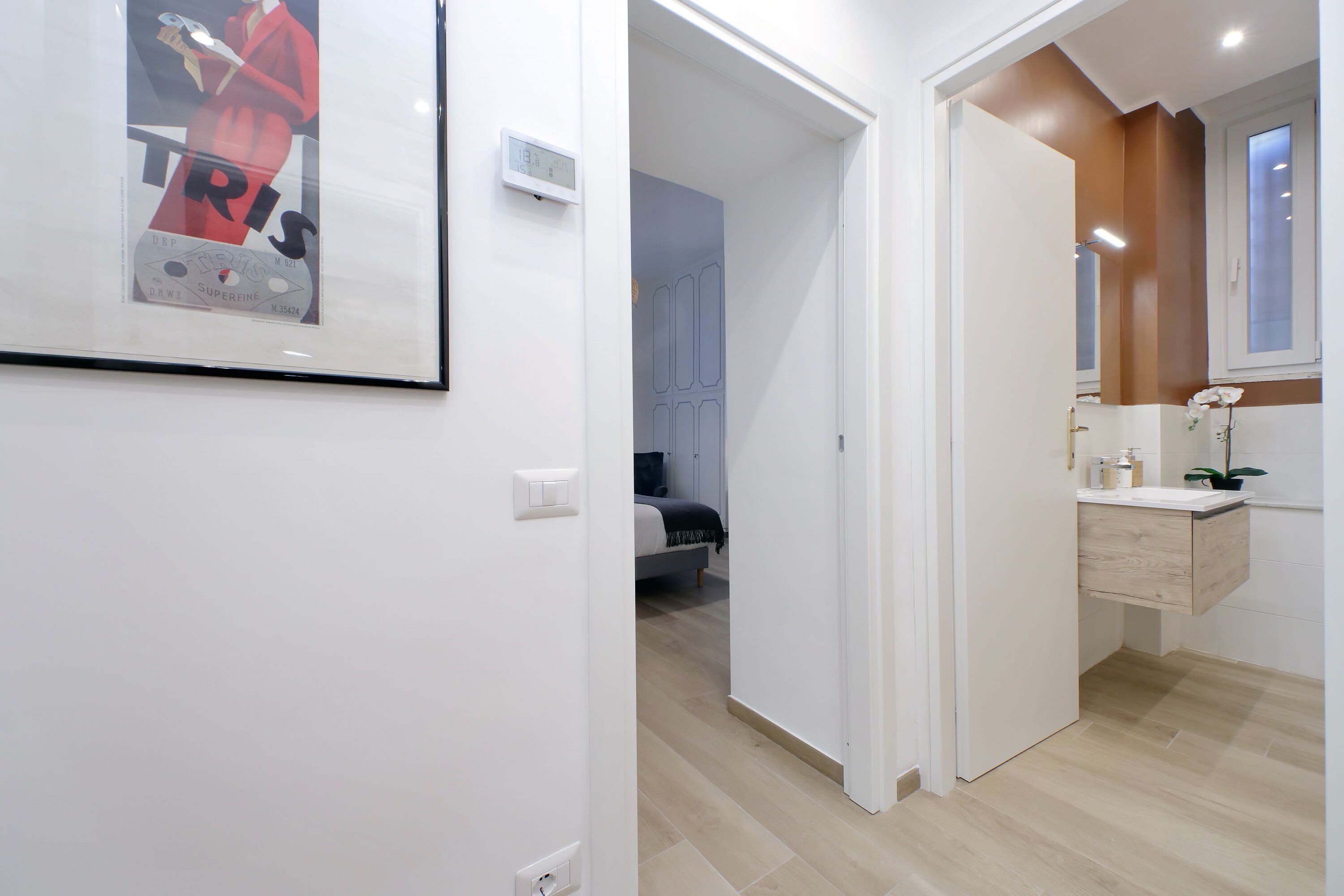 A modern bathroom with a wooden vanity, a mirror, and a small plant.
