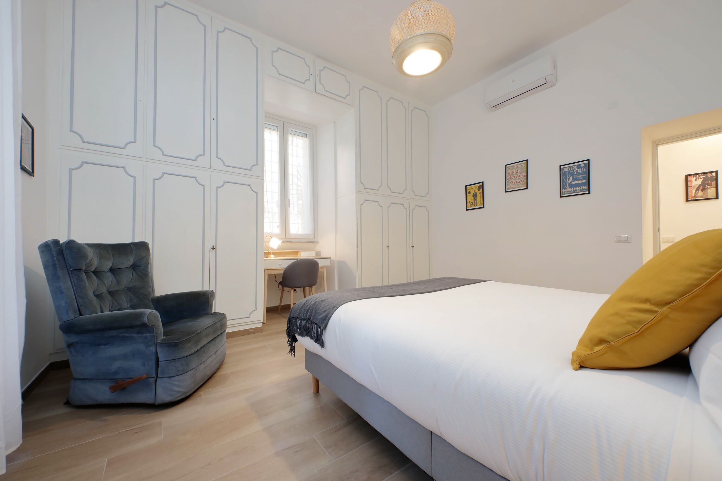 A bedroom with a bed, a chair, a desk, and a window.