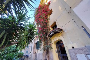 A narrow alley with a building on the right featuring a balcony with red flowers. - Brand new Vatican flat with terrace (Rome)