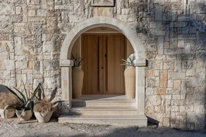 A stone building with a wooden door and steps leading to it. - 4 Bedroom | Casa Prasoul Contemporary Exclusive Villa with Private Heated Pool (Rethymno)