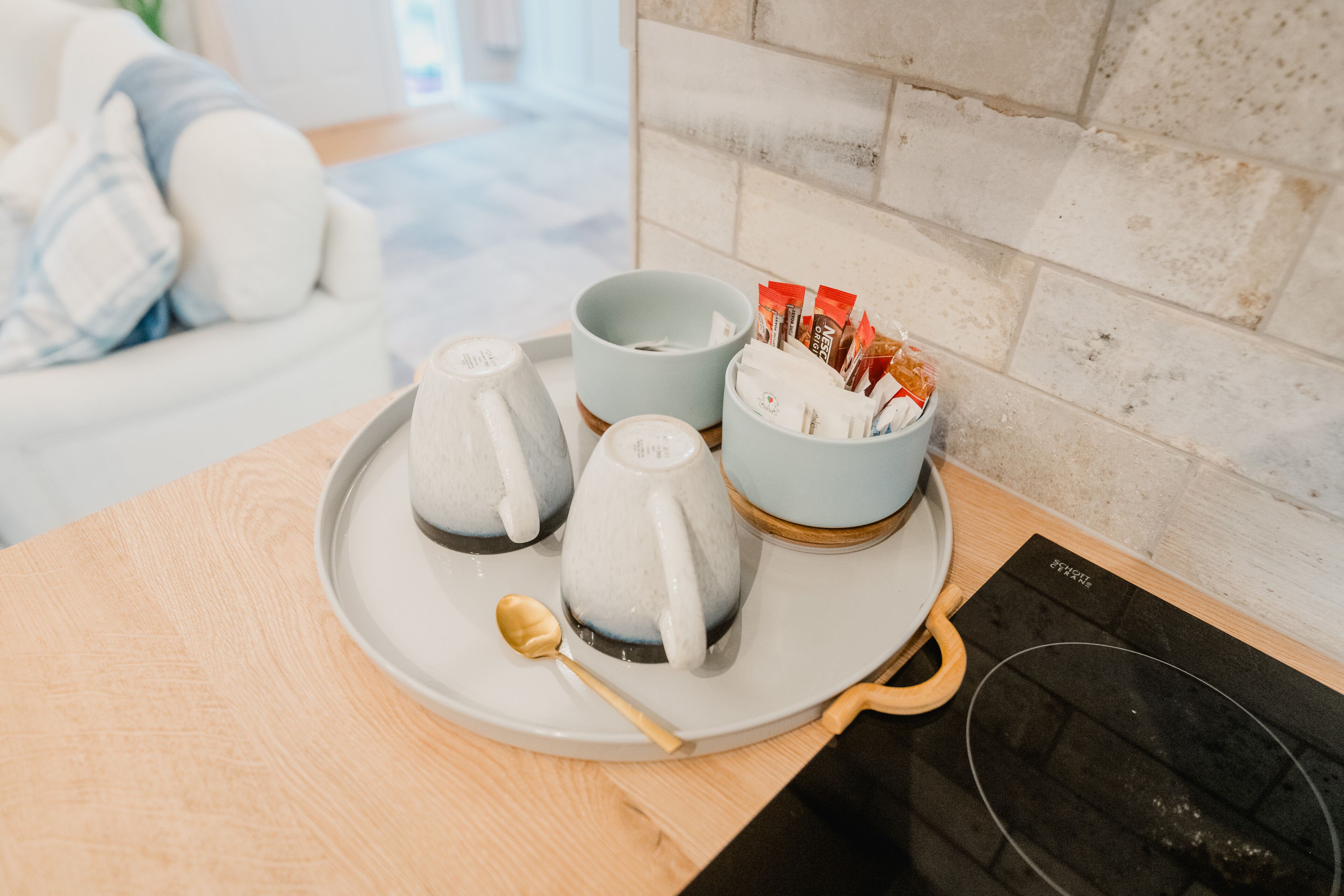 A tray with ceramic mugs and a honey dipper on a wooden table.