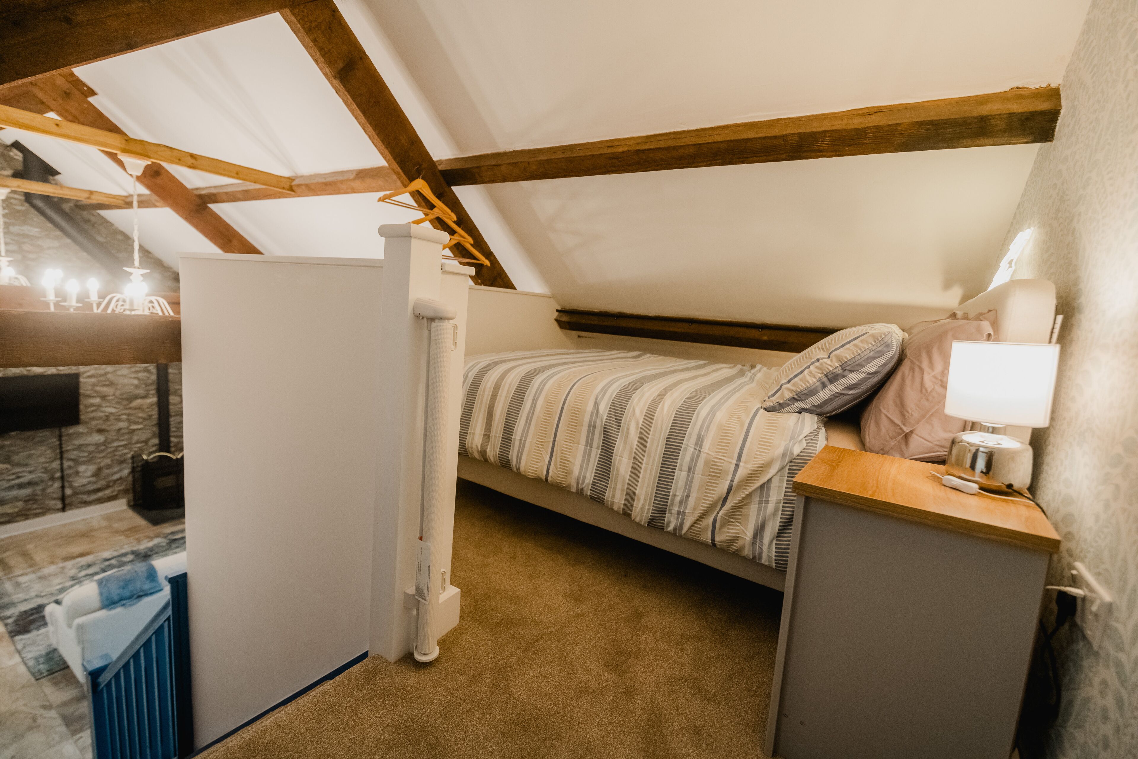 Une petite chambre mansardée, chaleureuse et accueillante, avec un lit simple, une table de chevet et un radiateur.