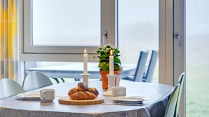 Un tavolo da pranzo con una candela, una pianta in vaso e un piatto di pasticcini.