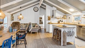 Ein geräumiger Lofts mit hohen Decken, einer Küche mit Holzarbeitsplatten, einem Essbereich mit großem Tisch und Stühlen sowie einer gemütlichen Sitzecke mit Sofa und Teppich.