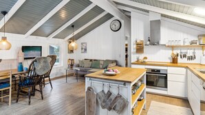 Ein geräumiger Loft mit hohen Decken, einer Küche mit weißen Schränken und einer gemütlichen Sitzecke mit Sofa und Sesseln.