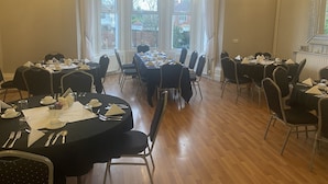 A conference room with round tables, chairs, and chandeliers. - The Salfordian Hotel (Southport)