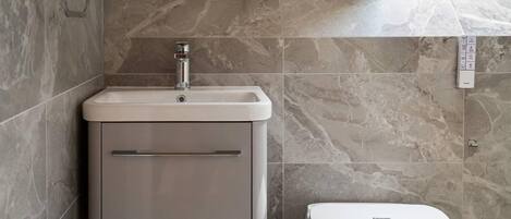 A bathroom with a built-in sink, a toilet, and a wall-mounted control panel.