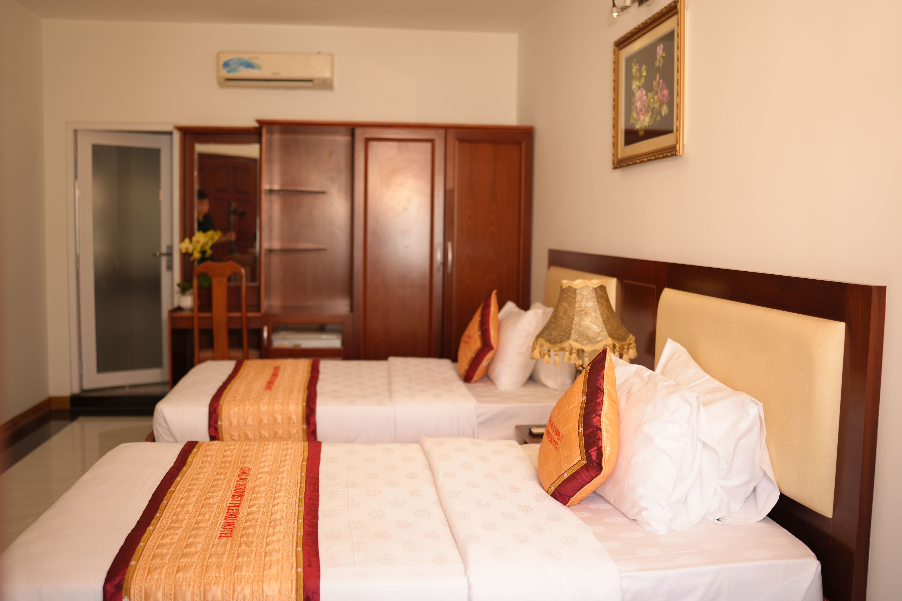 A hotel room with two beds, a wardrobe, a desk, and a chair.
