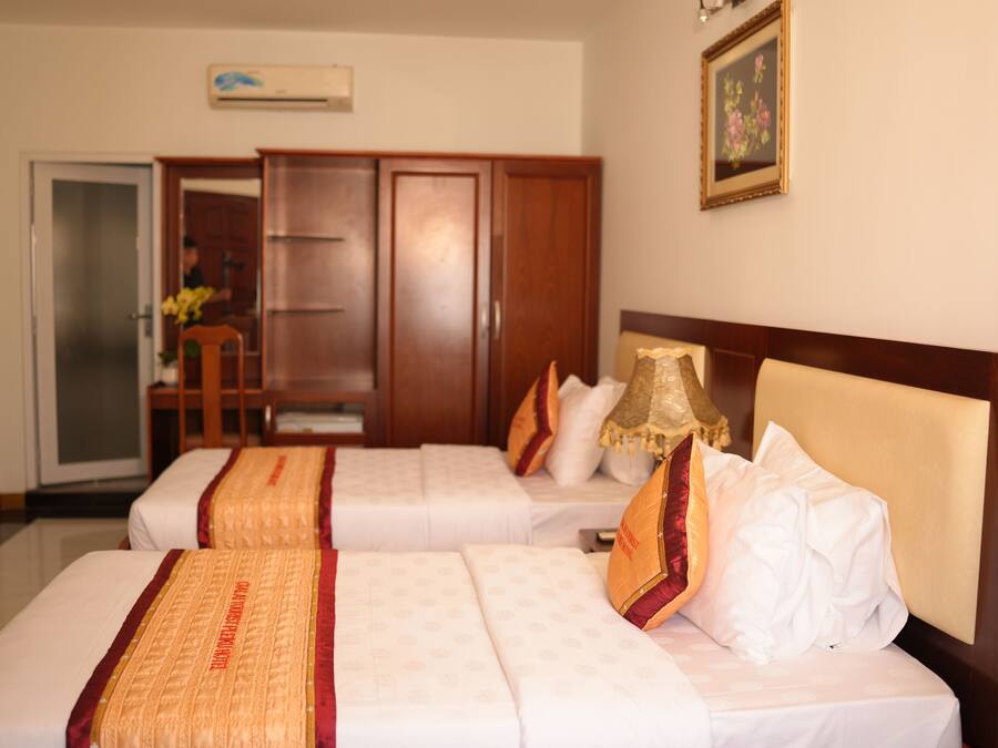 A hotel room with two beds, a wardrobe, a desk, and a chair.