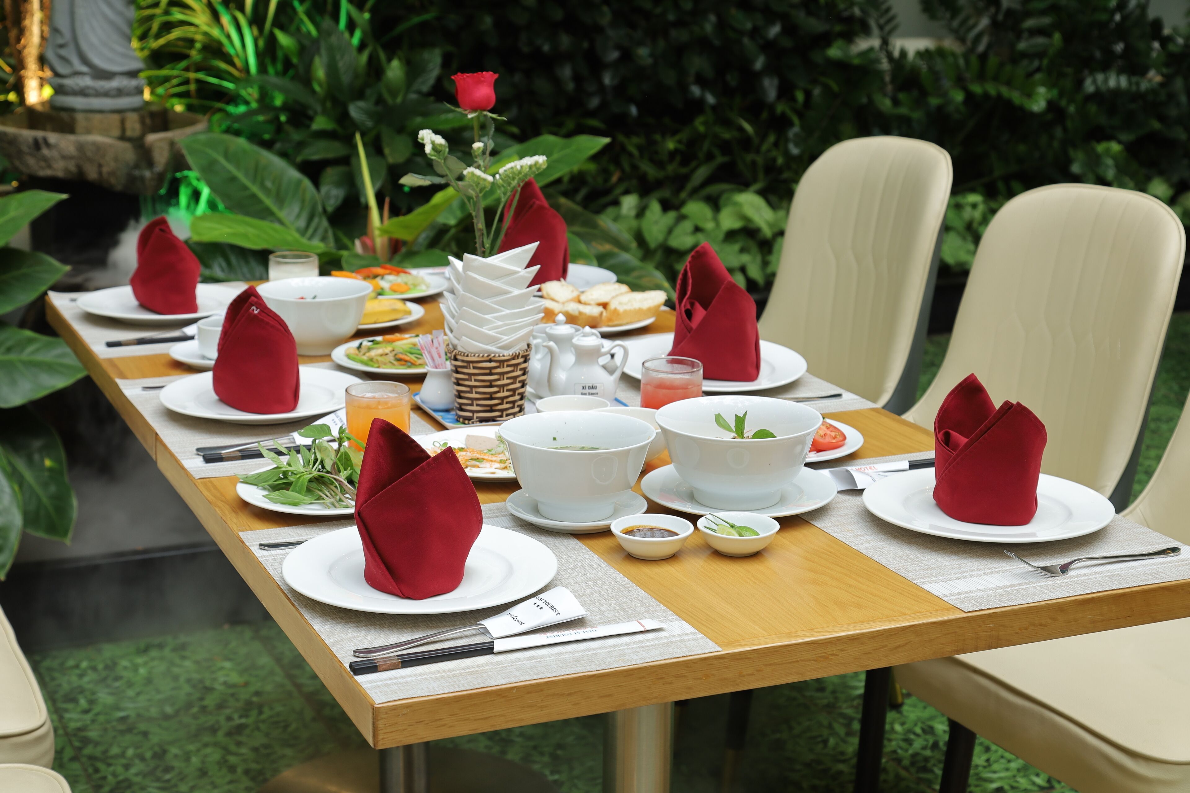 A dining table set with plates, bowls, and napkins, surrounded by chairs.